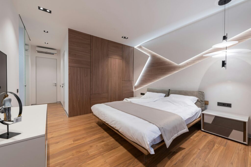modern hotel guestroom bed Light modern hotel room interior with soft white bed and wooden floor near cupboard